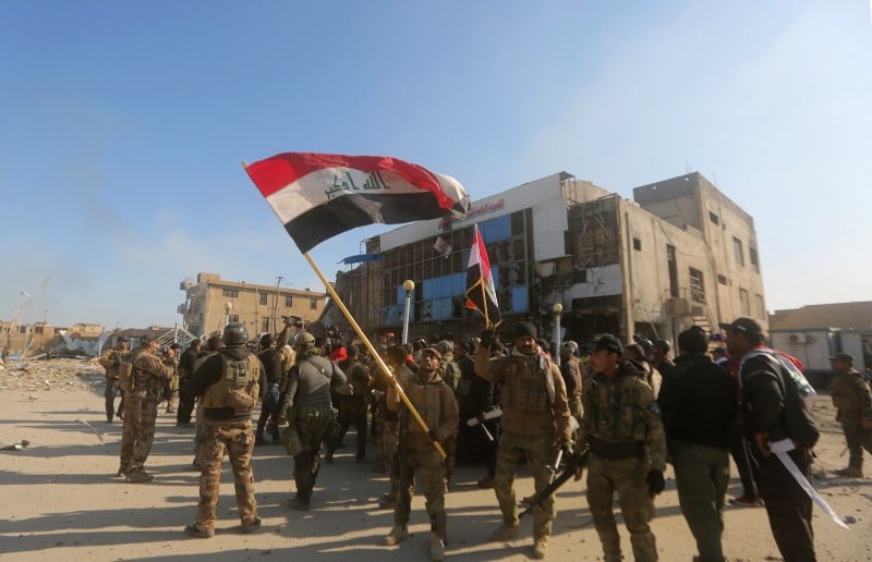 Soldados posam com a bandeira iraquiana após avanços na campanha