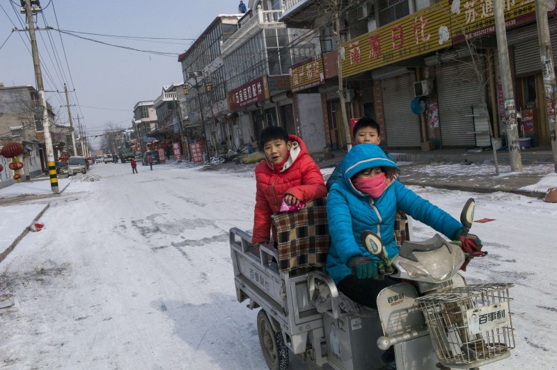  A woman rides a tricycle on a road at Tuntou village, on the outskirts of Shijiazhuang, Hebei province on January 22, 2016. Schools have been suspended and emergency workers put on standby in China as the country braces for historically cold weather, including 30-year lows in places, the government and state media said on January 21. The National Meteorological Center predicted temperatures would drop up to 10 degrees Celsius across much of the country over the next four days, according to a statement on its website.  AFP PHOTO / FRED DUFOUR  