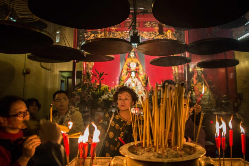  Visitors place joss sticks in urns in front of a shrine (back) while praying for good fortune for the coming year at the Man Mo Temple in Hong Kong on February 4, 2016, ahead of the Lunar New Year of the Monkey, which falls on February 8.  The temple, which was built in 1847, is a tribute to the God of Literature (Man) and the God of War (Mo). / AFP / ANTHONY WALLACE  