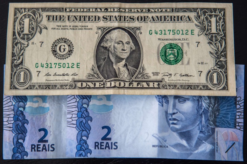  PICTURE DEPICTING US DOLLAR NOTES AND BRAZILIAN REALS AT THE EXCHANGE RATE OF ONE DOLLAR BILL PER 4, 03 REALS ON SEPTEMBER 22, 2015. THE BRAZILIAN REAL HIT AN ALL-TIME LOW TUESDAY, DIPPING IN VALUE TO 4.03 AGAINST THE DOLLAR WITHIN MINUTES OF THE MARKET'S OPENING AMID SNOWBALLING FEARS OVER A DEEPENING ECONOMIC CRISIS.  AFP PHOTO / CHRISTOPHE SIMON  