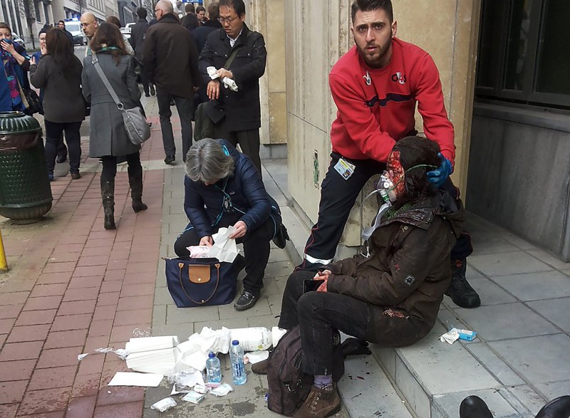  TOPSHOT - A private security guard helps a wounded women outside the Maalbeek metro station in Brussels on March 22, 2016 after a blast at this station located near the EU institutions.  Belgian firefighters said at least 26 people had died after "enormous" blasts rocked Brussels airport and a city metro station today, as Belgium raised its terror threat to the maximum level. / AFP PHOTO / Michael VILLA  