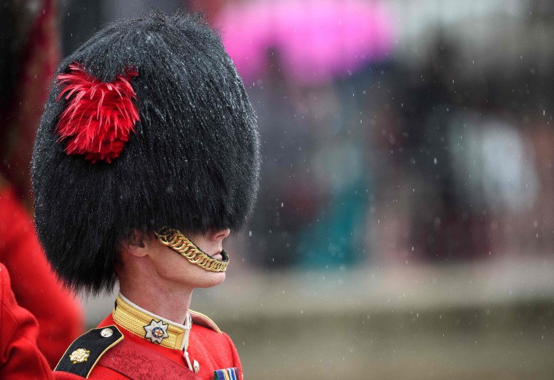 A foto mostra um guarda real sob forte chuva, esperando o retorno da Rainha Elizabeth II