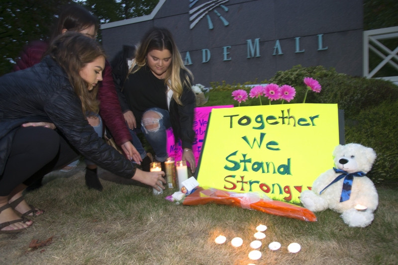 Amigos das vítimas acendem velas e colocam flores no lado de fora do shopping onde ocorreu a execução