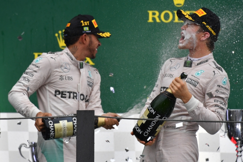 Mercedes AMG Petronas F1 Team's British driver Lewis Hamilton (L) celebrates after winning the Brazilian Grand Prix ahead of title rival and Mercedes teammate Nico Rosberg (R) and Red Bull Racing's Belgian-Dutch driver Max Verstappen at the Interlagos circuit in Sao Paulo, Brazil, on November 13, 2016. / AFP PHOTO / Nelson Almeida
      Caption