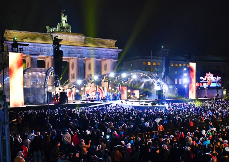Revellers wait for the start of a New Year concert celebration near the capital's Brandenburg Gate on December 31, 2016. / AFP PHOTO / dpa / Jens Kalaene / Germany OUT
      Caption