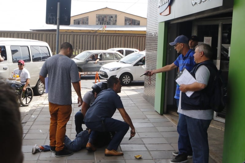 Pessoa que ajuda motoqueiro segura faca e outro o celular da vítima