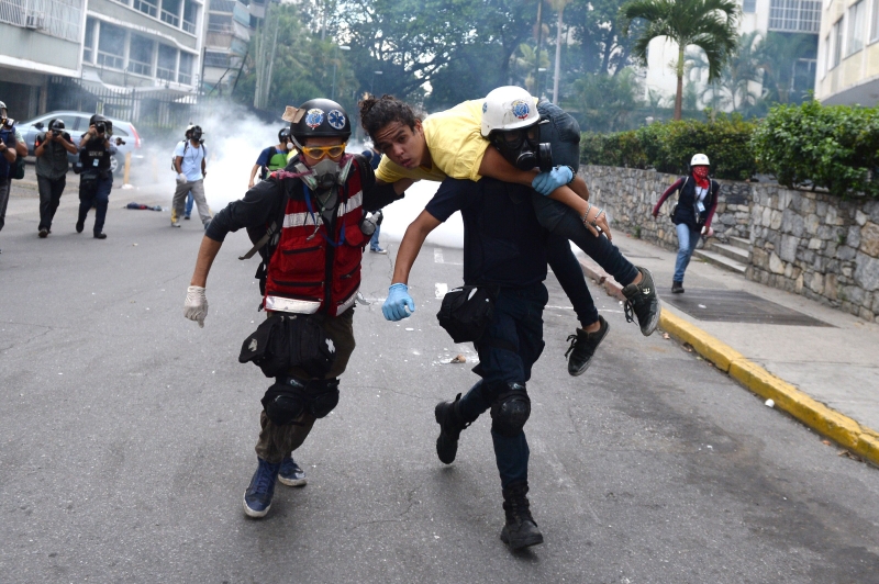 Médicos voluntários carregam manifestante ferido em Caracas