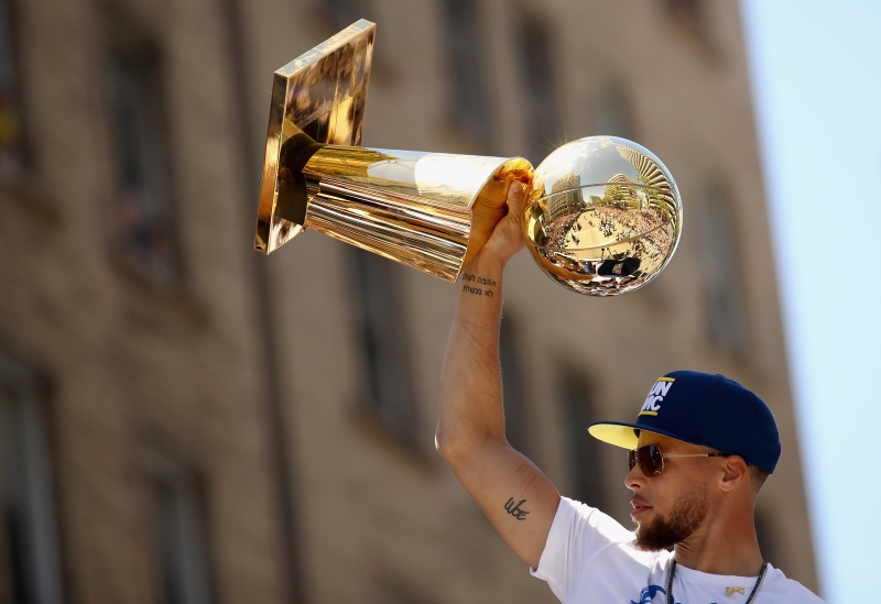 Stephen Curry ergue o troféu nas ruas de Oakland
