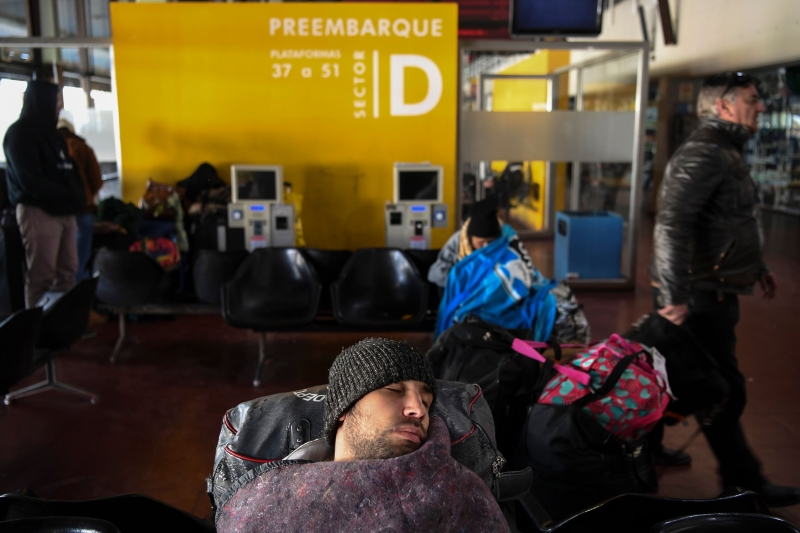A passenger sleeps at the closed Retiro train station in Buenos Aires on June 25, 2018, during a 24-hour general strike called by Argentina's unions in protest of the government's deal with the International Monetary Fund.
Although the General Confederation of Workers (CGT) called only for a strike, more radical groups organized demonstrations that cut off access to Buenos Aires. With no trains, subways, buses or flights in service, organizers expected at least one million workers to take part in the action. / AFP PHOTO / Eitan ABRAMOVICH
      Caption