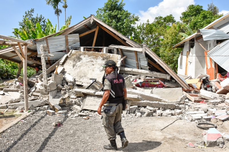 Segurança observa o restou das casas em uma vila de Lombok