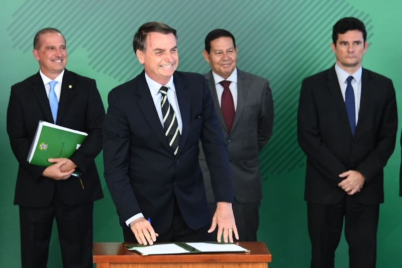 Bolsonaro, acompanhado pelo chefe de Estado, Onyx Lorenzoni, pelo vice-presidente, Hamilton Mourão e pelo ministro da Justiça, Sérgio Moro, durante assinatura do decreto de flexibilização da posse de armas