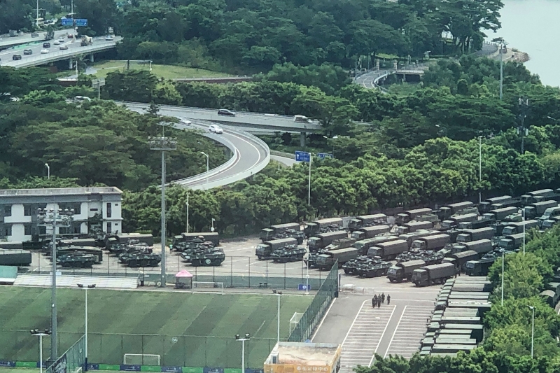 Policiais militares estão em um estádio de Shenzhe, rodeados por caminhões e blindados 
 
 
