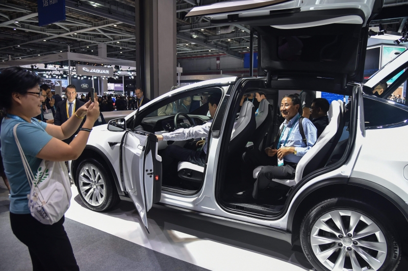 People check out a Tesla car in the Tesla stand during the second China International Import Expo in Shanghai on november 6, 2019. (Photo by HECTOR RETAMAL / AFP)
      Caption