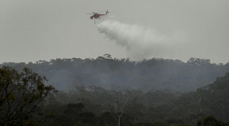 Helicóptero despeja água para conter queimadas