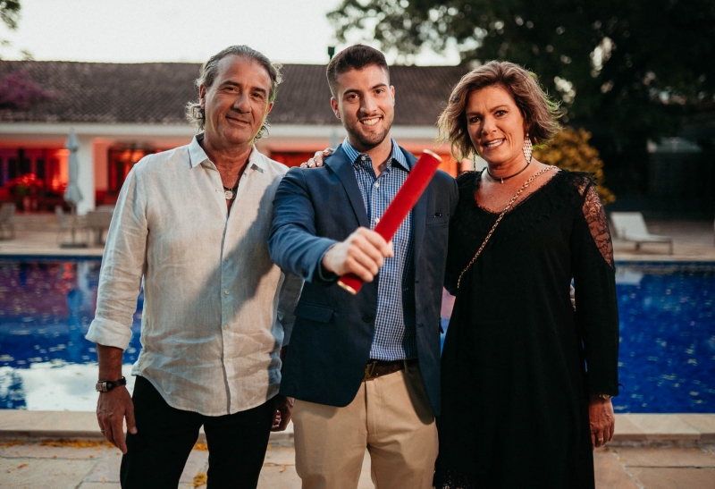 Ricardo Feijó entre os pais, Paulo Zago e Du Feijó, comemorando o canudo
