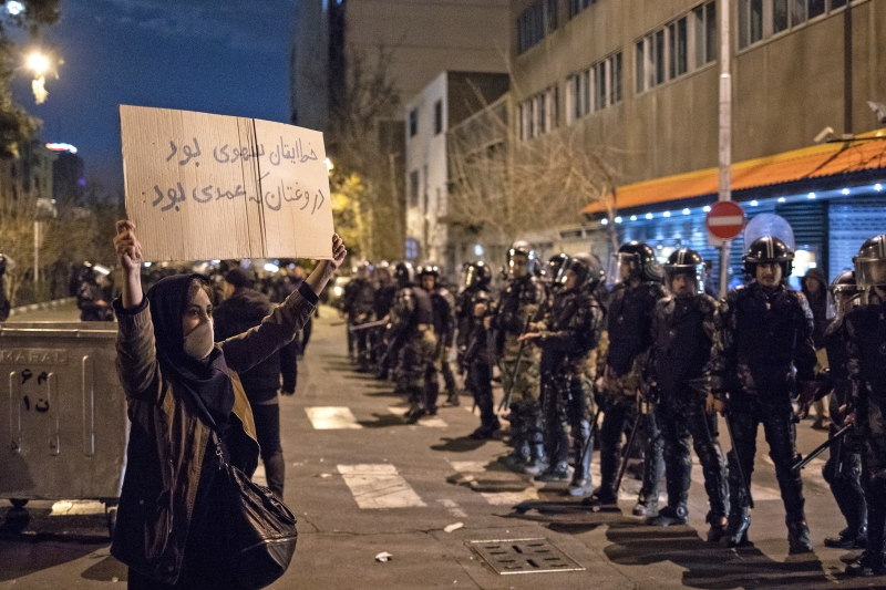 Iraniana segura cartaz escrito "seu erro foi não intencional, sua mentira foi intencional" em protesto
