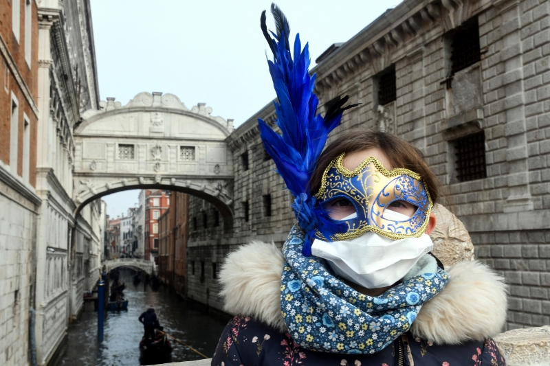 Com as mortes na Itália, turistas agregam a máscara de proteção à fantasia do Carnaval de Veneza 