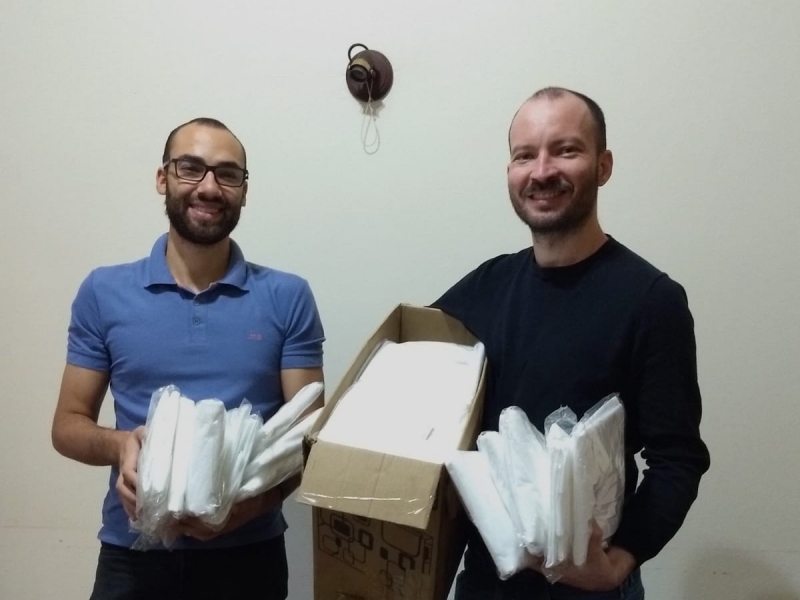 Henrique Knorst (d) e Marcelo Mendes (e), voluntários do projeto, recebem doações de TNT