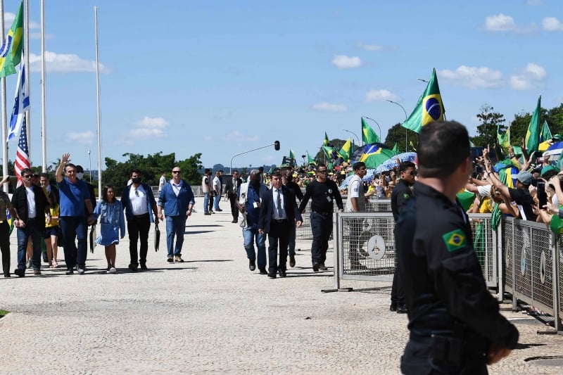 Brazilian President Jair Bolsonaro (2-L), holding his daughter Laura's hand, waves at supporters gathering outside Planalto Palace in Brasilia, on May 3, 2020 during the COVID-19 novel coronavirus pandemic. - The novel coronavirus has killed at least 243,637 people since the outbreak first emerged in China last December, according to a tally from official sources compiled by AFP at 1100 GMT on Sunday. (Photo by EVARISTO SA / AFP)