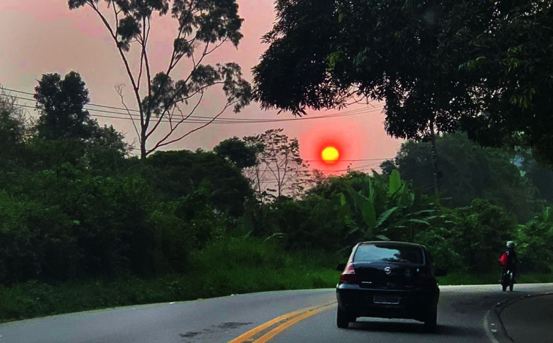 Céu impregnado pela fumaça, que envolve o sol visto da estrada do litoral paulista, em São Sebastião