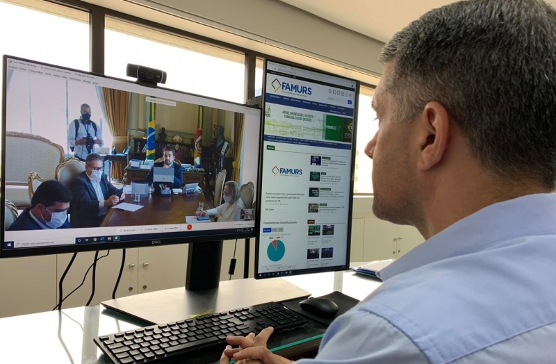Leite, na transmissão em vídeo, apresenta medidas em reunião com o presidente da Famurs (direita)