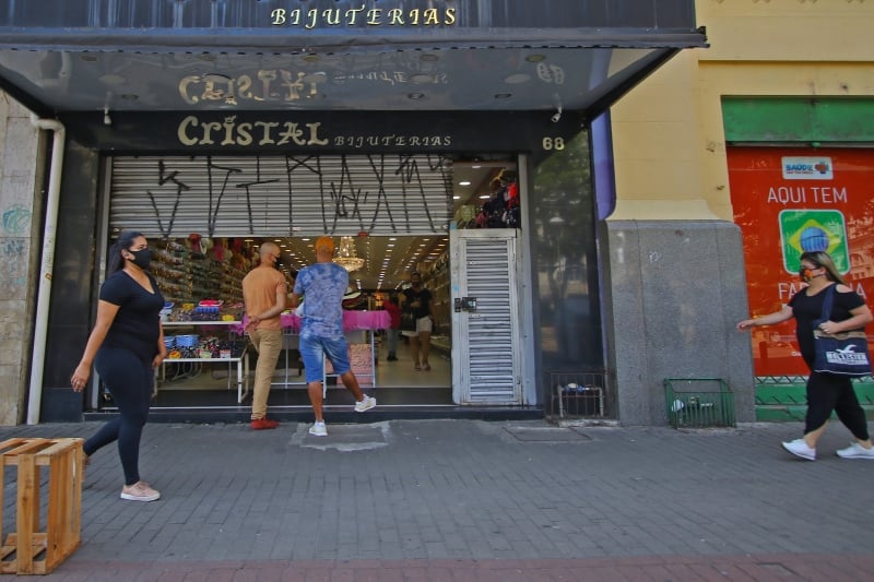 Estabelecimento opera com parte da grade baixada e com clientes nos corredores internos