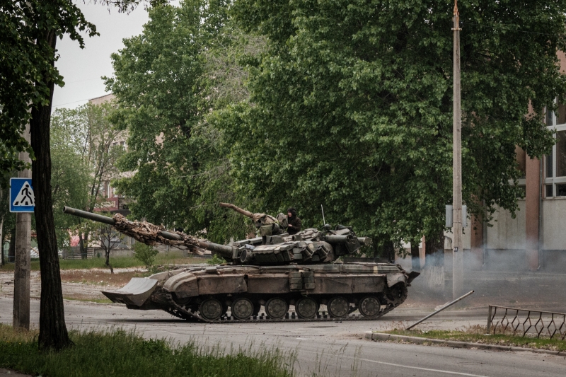 TOPSHOT - A Ukrainian main battle tank drives on a street during nearby mortar shelling in Severodonetsk, eastern Ukraine, on May 18, 2022, on the 84th day of the Russian invasion of Ukraine. (Photo by Yasuyoshi CHIBA / AFP)