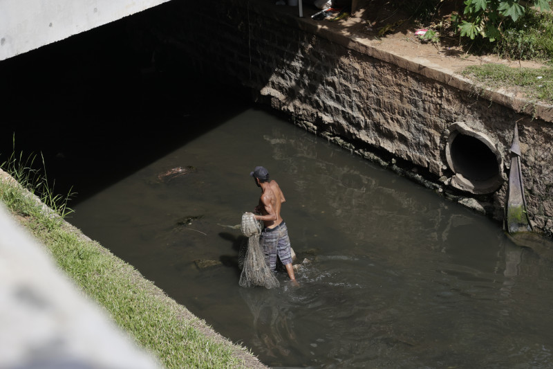 Homem pesca no Arroio poluído com tarrafa, ao lado do Shopping Pontal.  