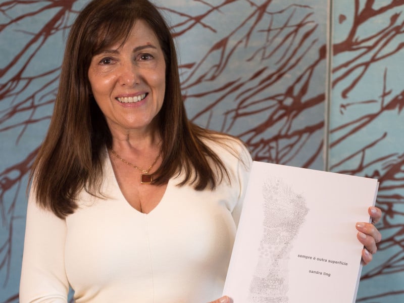 Sandra Ling, segurando exemplar do livro de sua autoria: 