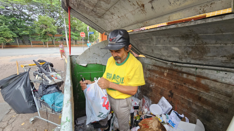 José Nunes busca plástico e latinhas dentro de contêineres de lixo