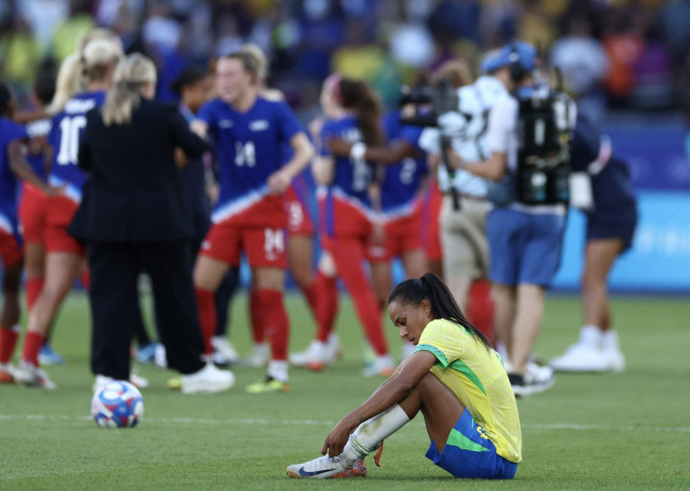 A jogadora Thais lamenta a derrota para os EUA, enquanto as norte-americanas comemoram o ouro
