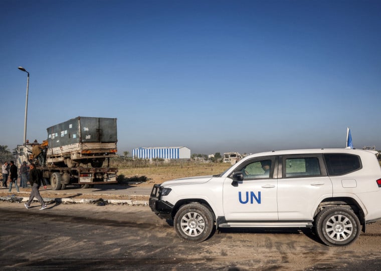 A United Nations' vehicle is parked nearby as a destroyed truck that was reportedly used by workers of the UN Relief and Works Agency for Palestine Refugees (UNRWA), which was fired upon by Israeli forces earlier, is loaded onto the back of a trailer vehicle, along Gaza's main Salah al-Din road outside Deir el-Balah in the centre of the Gaza Strip on October 23, 2024 amid the ongoing war in the Palestinian territory between Israel and Hamas. (Photo by Eyad BABA / AFP)