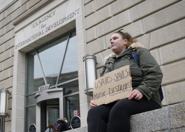 "Usaid salva, Musk destrói", diz cartaz de manifestante em frente à sede da agência