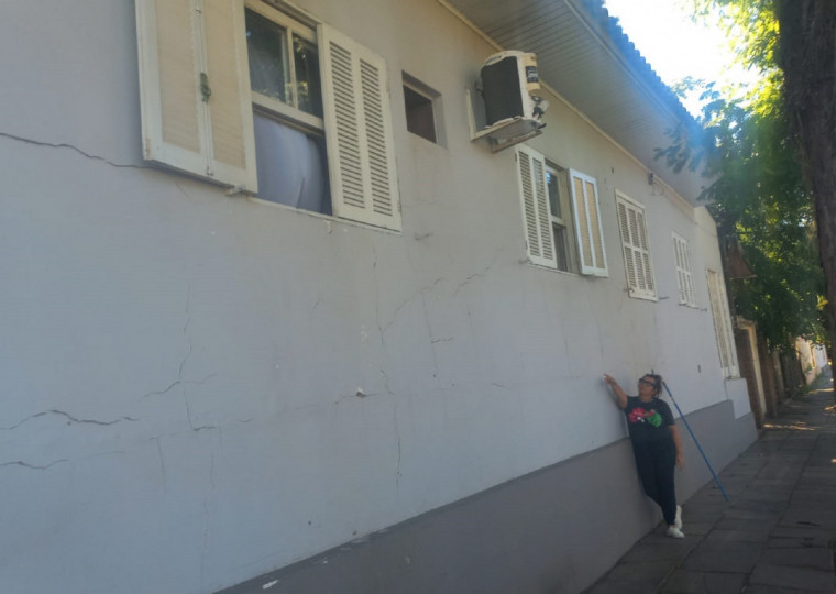 Zoraia Câmara mostra rachaduras e simula a altura da água do Rio Caí, que chegou a 17,60 metros em maio