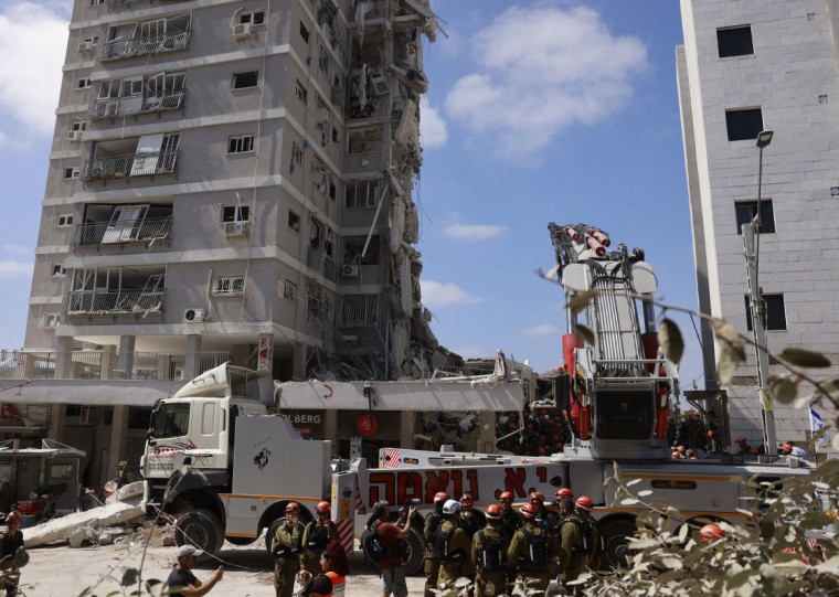 Equipes de resgate israelenses vasculham os escombros no local de um ataque noturno com mísseis iranianos em Bat Yam