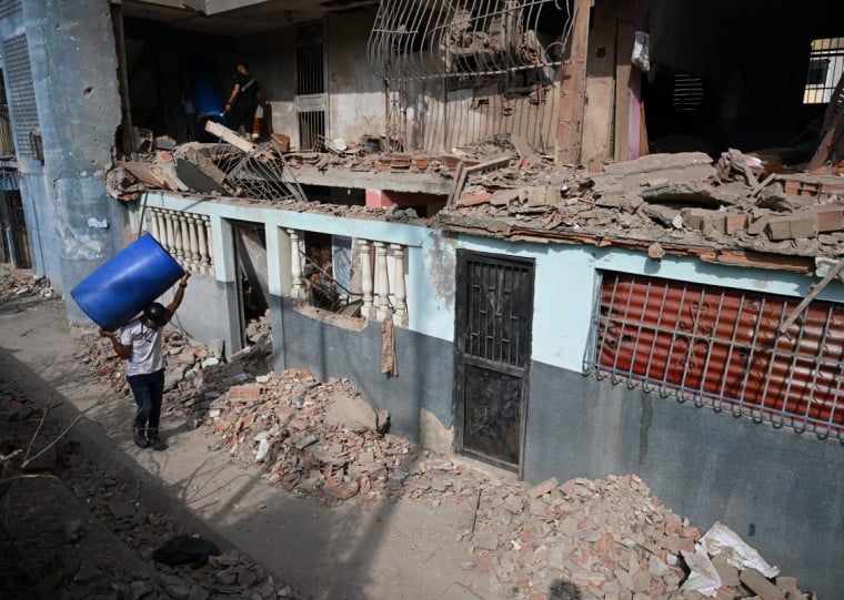 No estado de La Guaira pessoas limpavam casas atingidas por bombardeios neste domingo