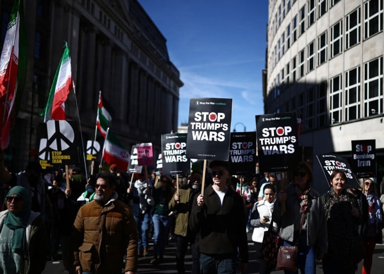 Manifestantes carregam cartazes em marcha em Londres pedindo o fim dos bombardeios ao Ir&atilde;