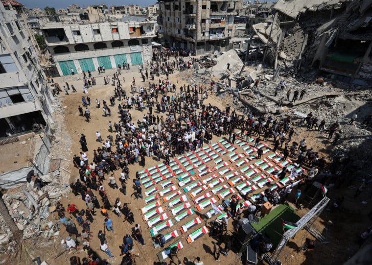  Palestinian mourners attend the funeral of members of the Abu Sharia and al-Hasayna families, whose remains were recently recovered from the rubble of residential buildings in the al-Sabra neighbourhood which were struck by Israeli bombardments in November 2023, in Gaza City on August 4, 2026. Hundreds of people attended the funeral ceremony, where music played from speakers at a site where Israeli strikes in late 2023 killed the 112 people, including 44 children all belonging to the same extended family from under the rubble. An October ceasefire remains in place between Israel and Hamas, but it has not halted the violence in Gaza. Efforts to secure a lasting agreement to end the war have stalled. (Photo by Omar AL-QATTAA / AFP)
