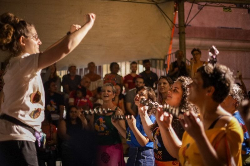 Oficina combina aquecimentos vocais, aprendizado de canção coletiva e práticas percussivas com instrumentos usados pela escola.