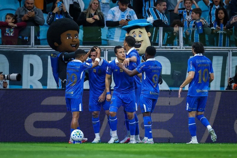 De virada, elenco gremista comemora os tr&ecirc;s pontos diante da sua torcida