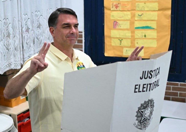 O candidato do PL Flávio Bolsonaro faz o sinal de vitória após votar em uma escola do Rio de Janeiro