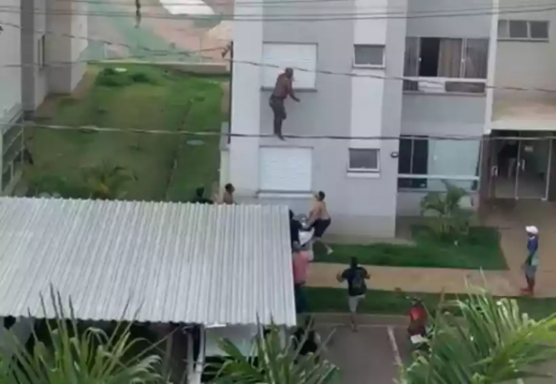 Momento em que o avô pula do quarto andar, antes de cair sobre colchões